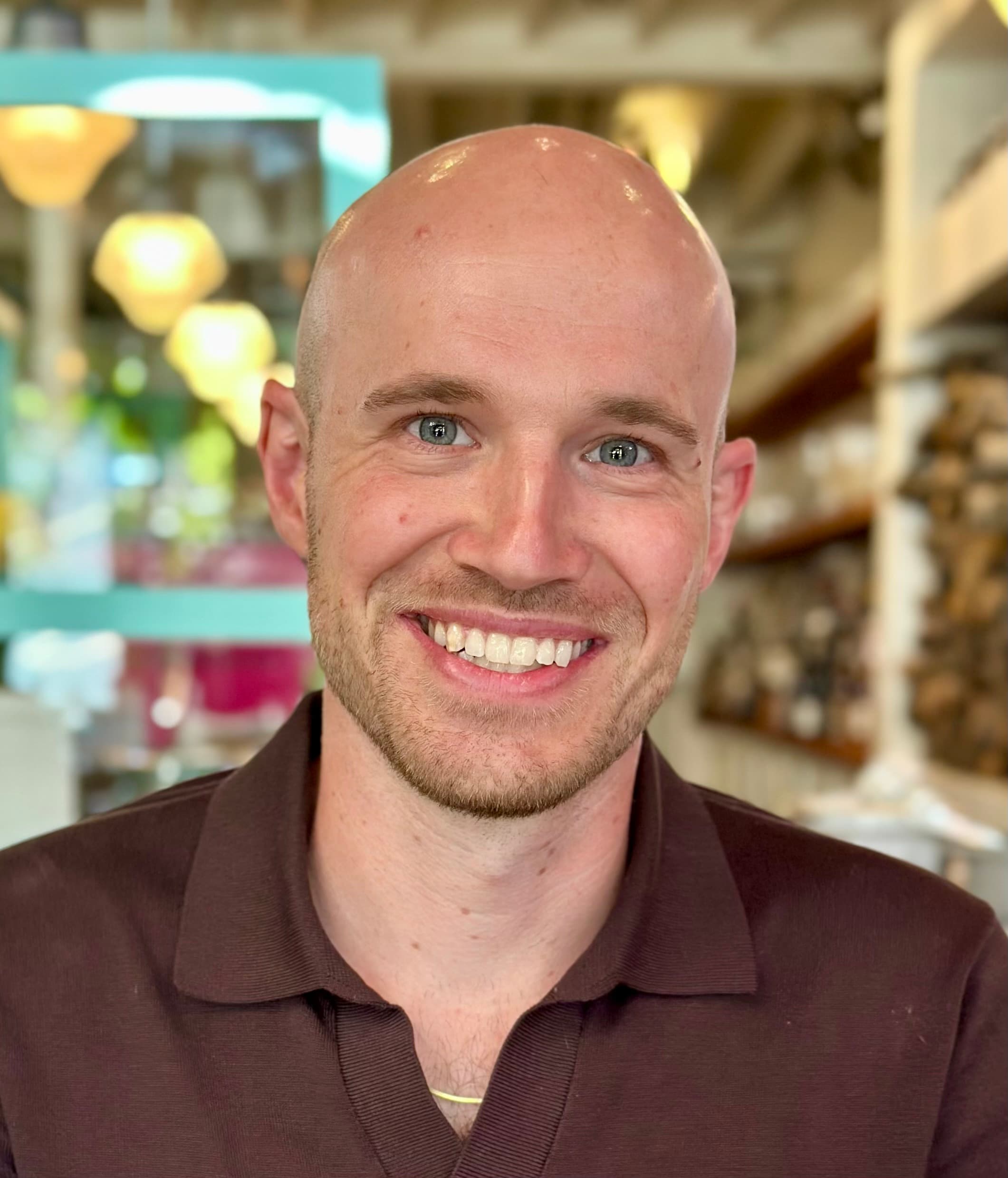 Andrew Shenstone smiling in a warmly lit indoor setting